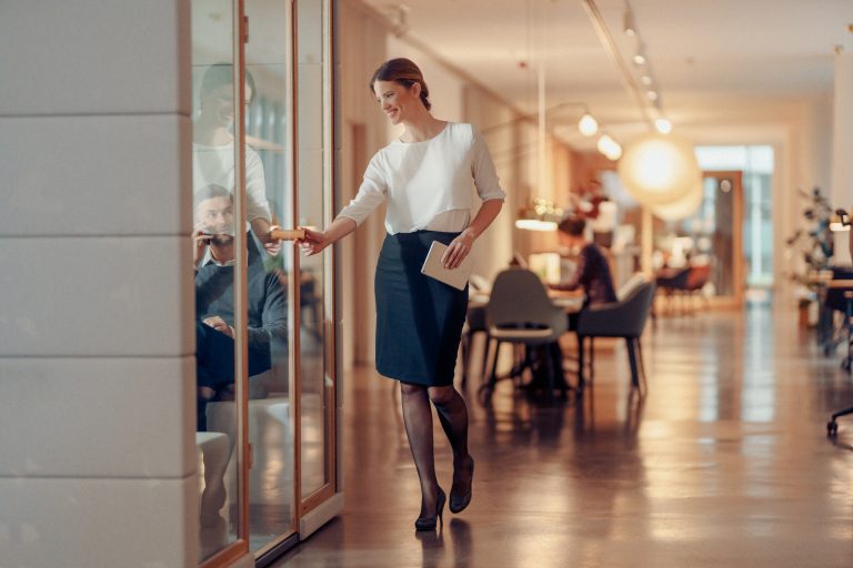 Frau öffnet schallgedämmte Meetingbox im modernen Büro