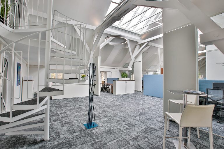 Spiral-Treppe im modernen Büro mit Glasdach und offenen Arbeitsbereichen