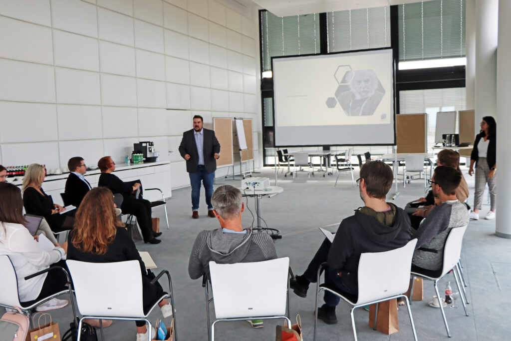 Workshop-Szene: Vortragender spricht vor Teilnehmern in einem modernen Raum.