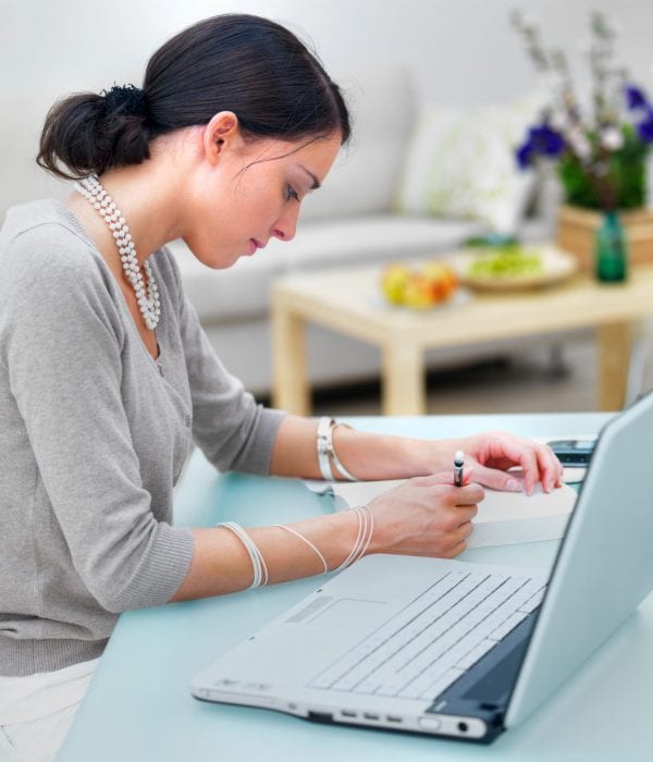 Side profile of a businesswoman writing notes at table Side profile of a businesswoman writing notes at table